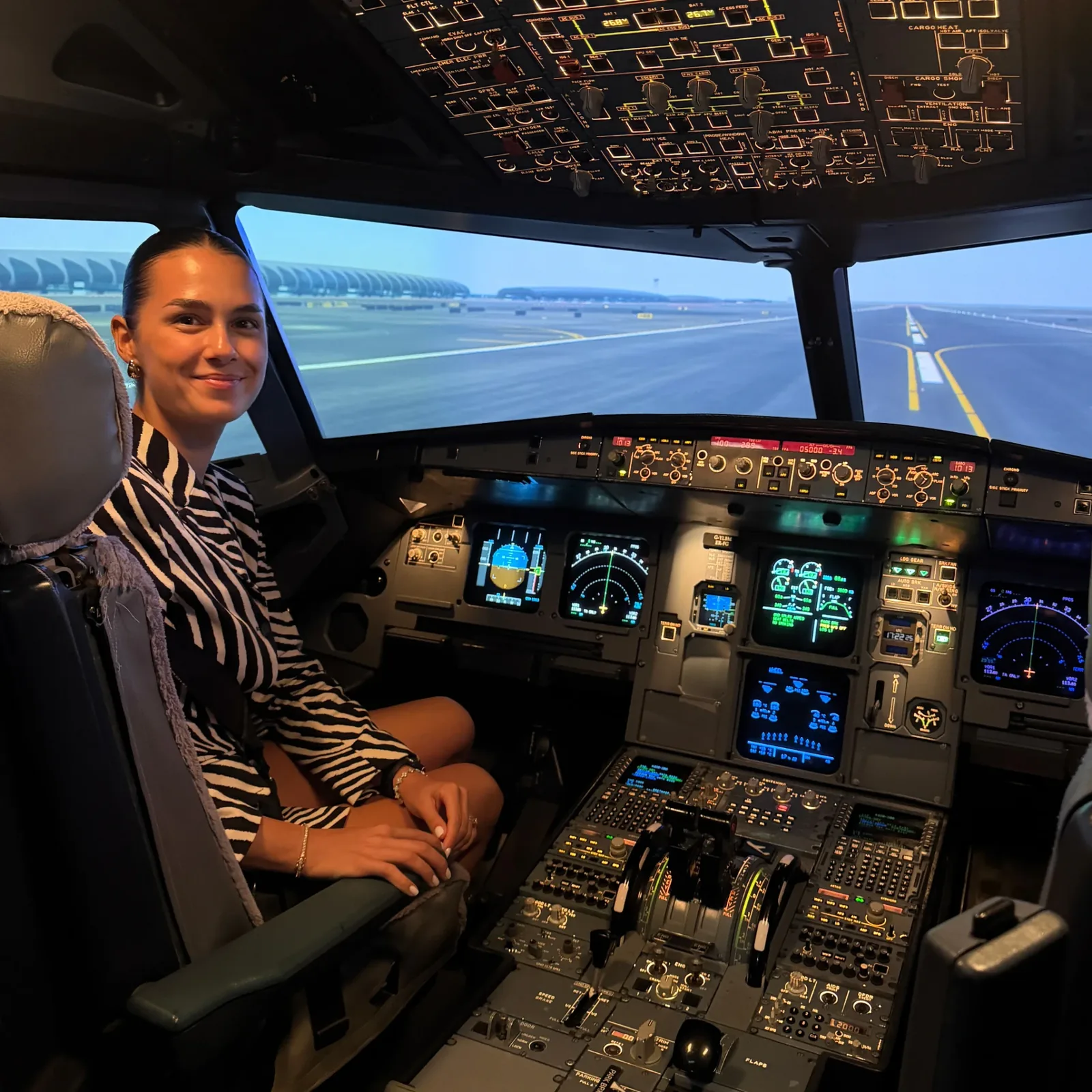 Emilia in the captain's seat of the A320 simulator, runway ahead